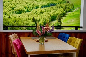 A dining area with a table, chairs, and a vase of flowers.