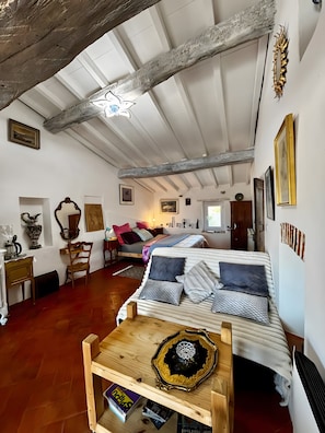 Une pièce chaleureuse avec un lit, des meubles en bois et un plafond avec des poutres apparentes.