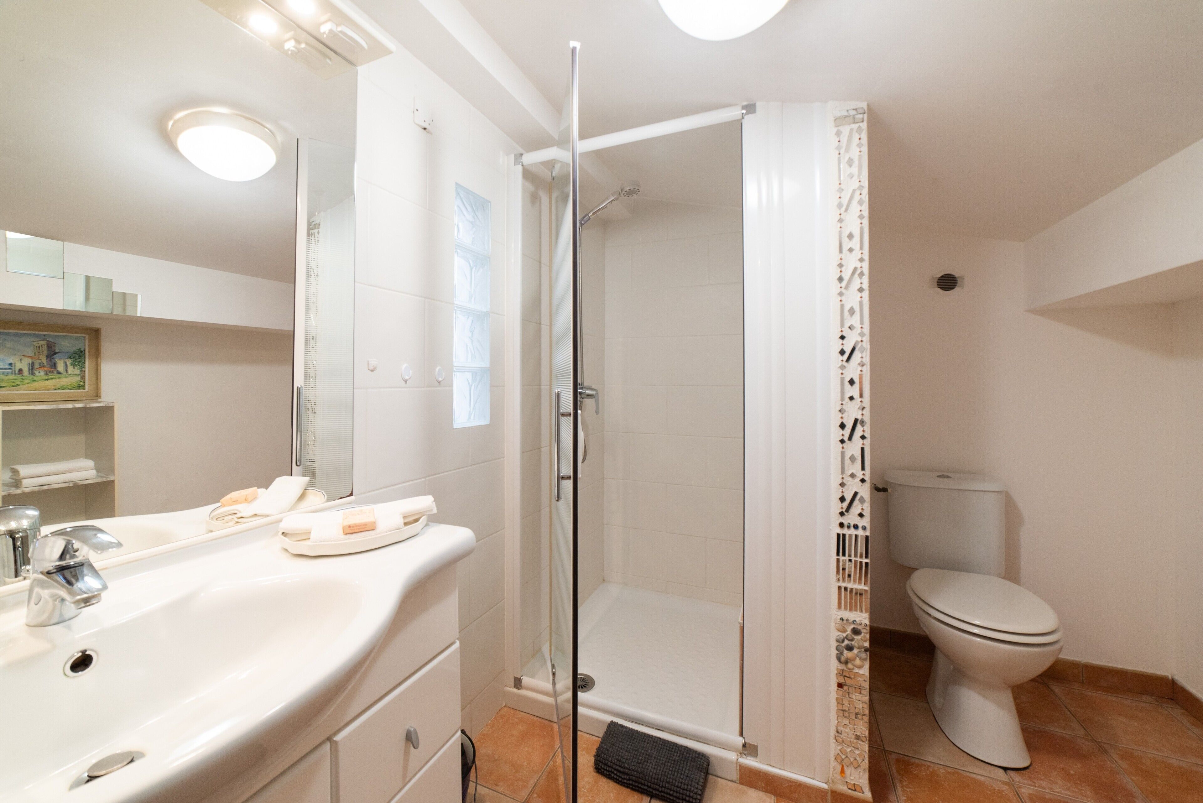 A bathroom with a shower, toilet, sink, and mirror.