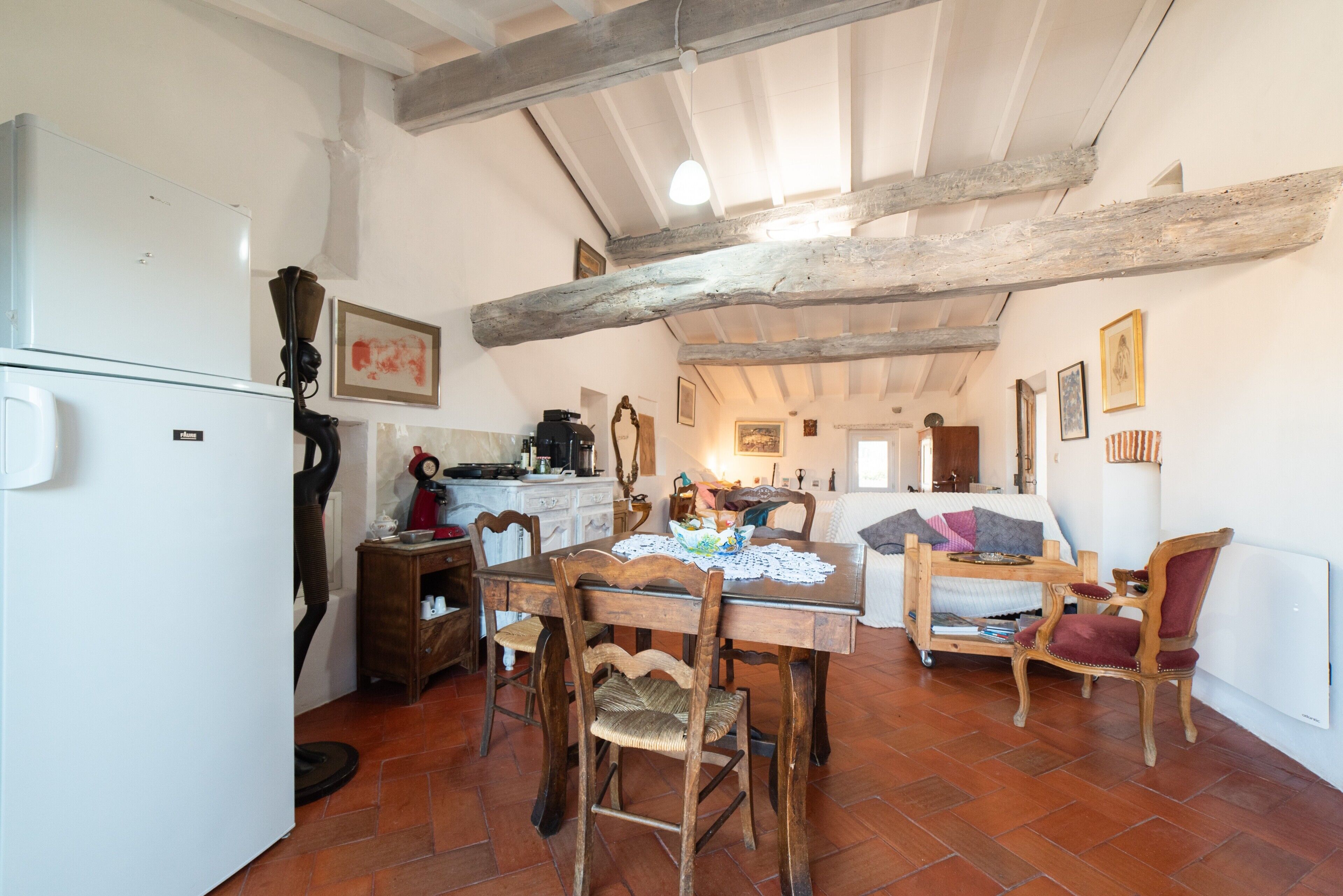 A rustic kitchen with a wooden table, chairs, and a white refrigerator.