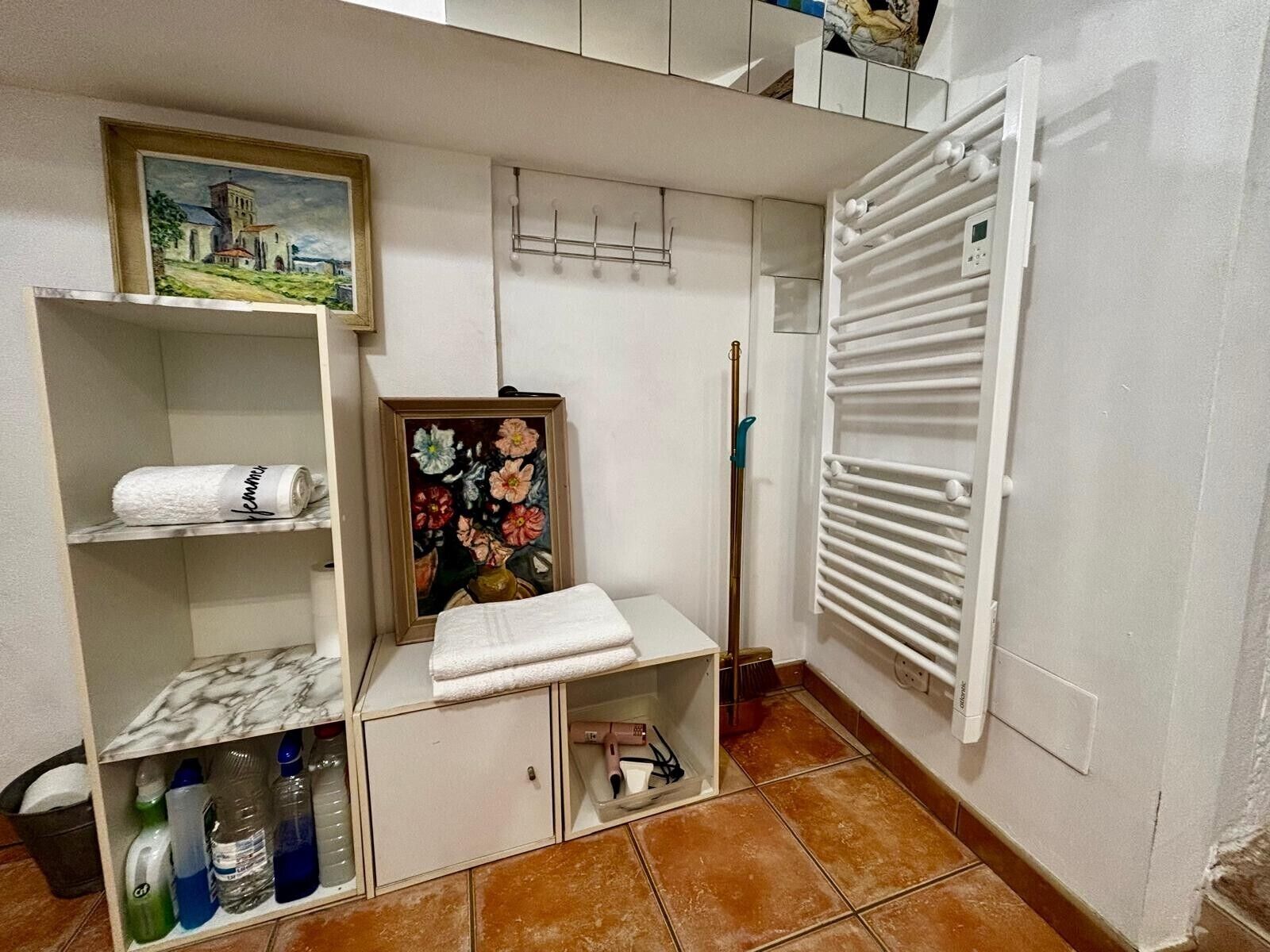 Un bagno con il water, un lavandino, un porta asciugamani, un quadro incorniciato e un termosifone.