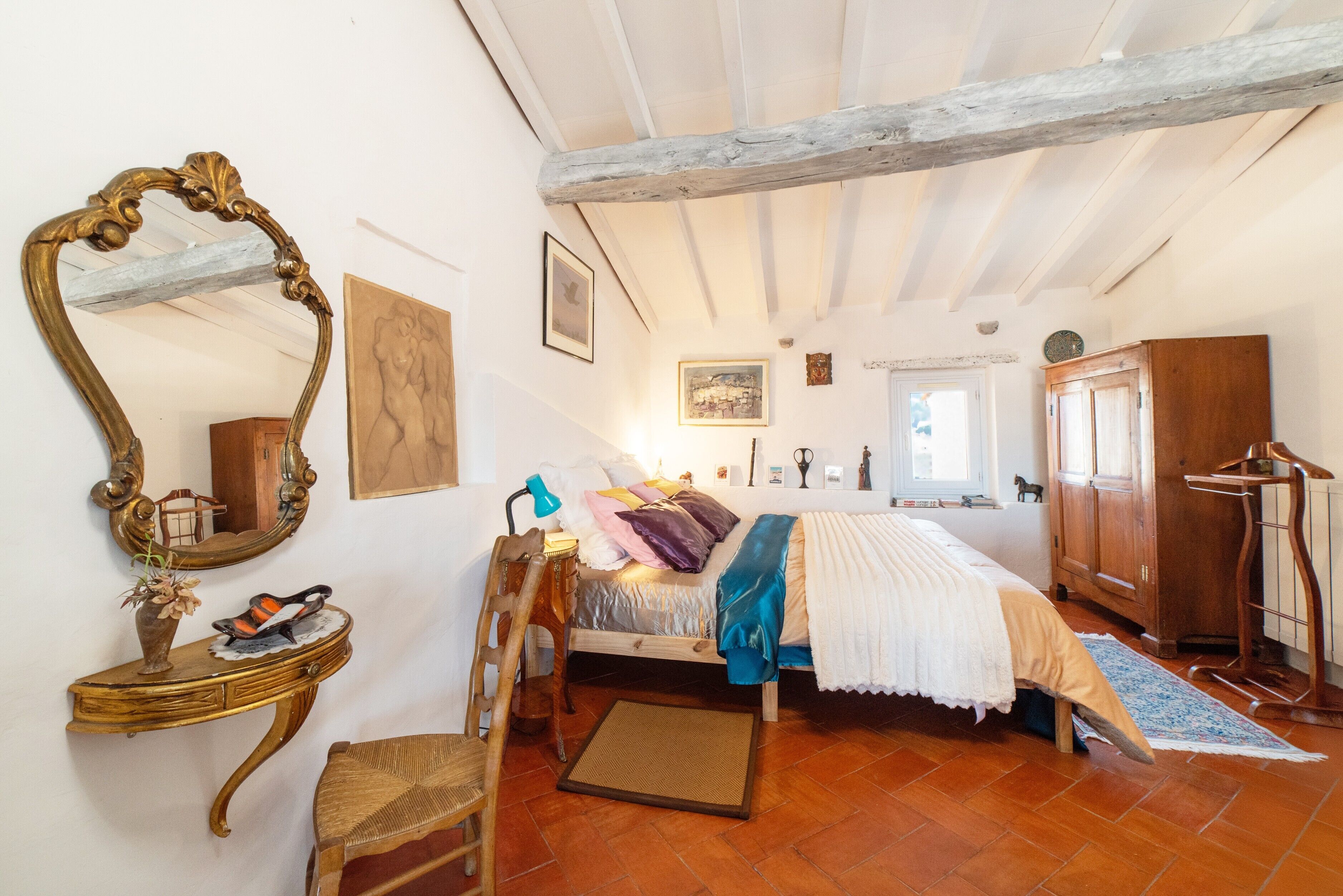 Un dormitorio con una cama, un aparador, una tocador con espejo y una silla.