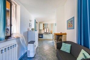 A compact living space with a kitchenette, a dining area, and a sofa with cushions.