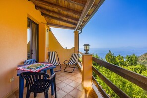 A balcony with a table and chairs, a view of the sea, and a wooden railing. - Apartment 'Mandarino' with Sea View, Private Terrace and Wi-Fi (Gioiosa Marea)