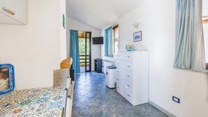 Una habitación con una cama, un aparador, un televisor y una ventana con cortinas.