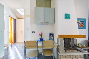 A dining area with a table, chairs, a cabinet, a fireplace, and artwork on the wall.
