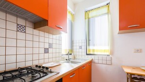 Cucina con piano cottura a gas, lavello e pensili arancioni.