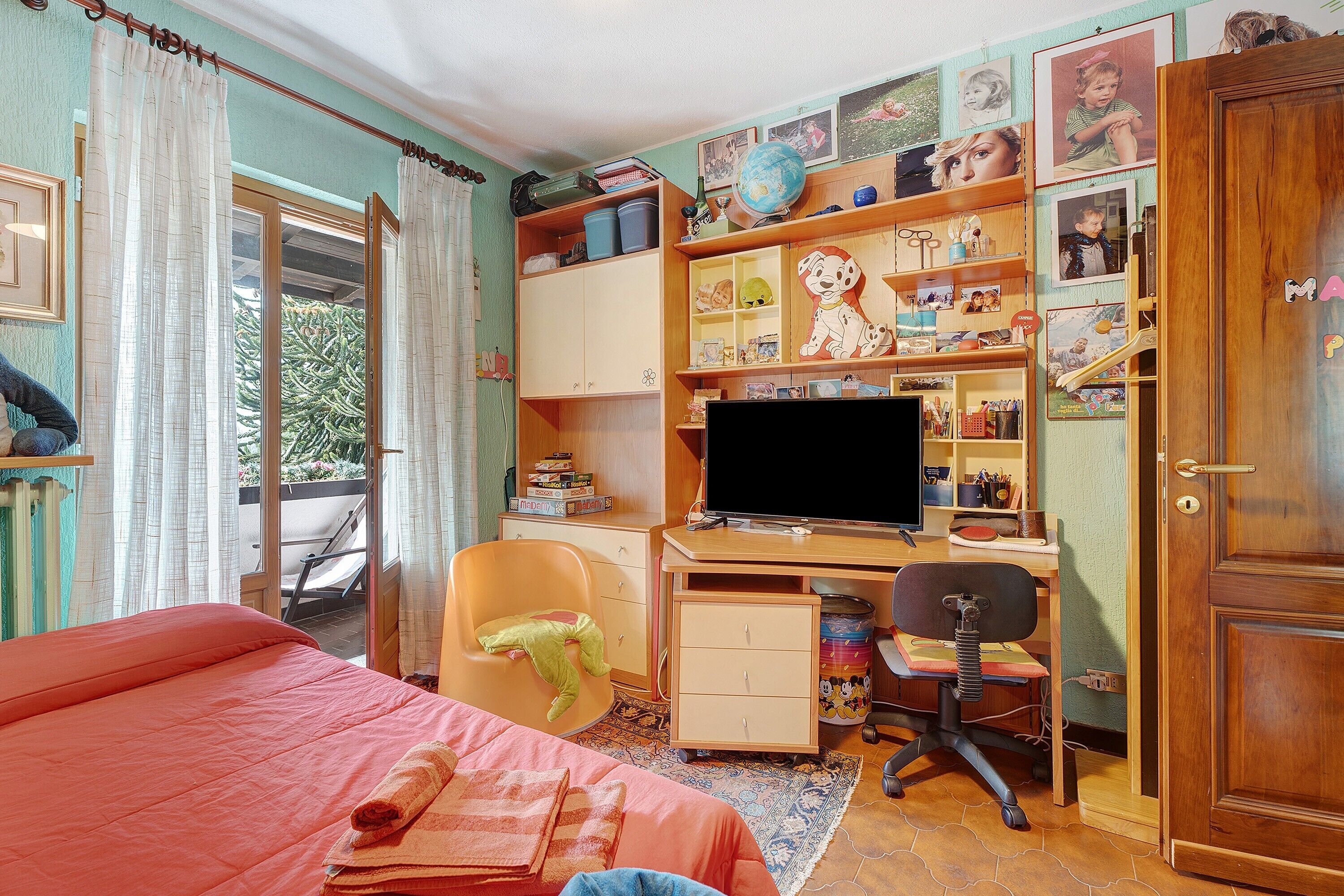 A bedroom with a bed, a desk, a chair, a television, and a wardrobe.
