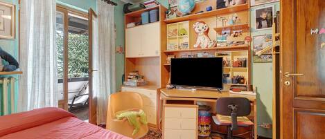 A bedroom with a bed, a desk, a chair, a television, and a wardrobe.
