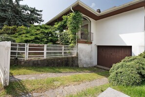 A house with a stone pathway, a wooden gate, and a dark brown garage door.