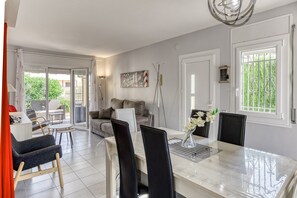 A modern dining area with a marble table, black chairs, and a vase of flowers. - Holiday Home 'Casa 3 Dormitorios' with Mountain View, Wi-Fi and Air Conditioning (L'Escala)