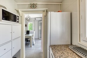 A kitchen with white cabinets, a microwave, a refrigerator, and a dining area with a table and chairs.