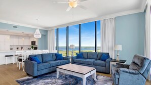 Un salon moderne avec deux canapés, une table basse et une vue sur l’océan.