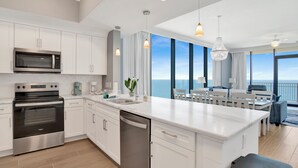 Une cuisine moderne avec des meubles blancs, des appareils en acier inoxydable et un grand îlot central.
