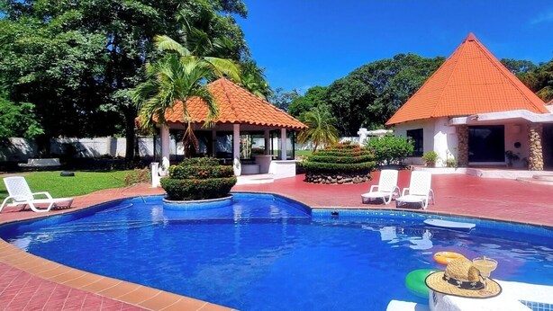 A swimming pool with lounge chairs, a gazebo, and a building with a red roof. - B&B Casa de Campo Mía, just steps from the beach! (Nueva Gorgona,)