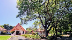 A traditional building with a red-tiled roof, surrounded by lush greenery and a well-maintained garden. - B&B Casa de Campo Mía, just steps from the beach! (Nueva Gorgona,)