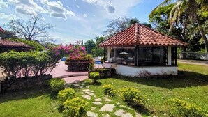 A gazebo with a tiled roof, surrounded by lush greenery and a stone pathway. - B&B Casa de Campo Mía, just steps from the beach! (Nueva Gorgona,)