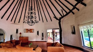 A spacious living room with a high ceiling, a chandelier, and a view through a large window. - B&B Casa de Campo Mía, just steps from the beach! (Nueva Gorgona,)