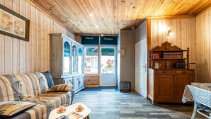 A cozy room with a sofa, a small table with a cup, a wooden cabinet, and a door leading to a shop.