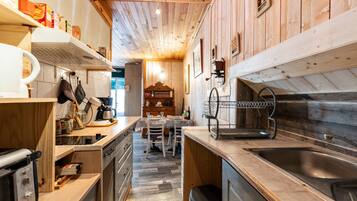 Une cuisine avec des meubles en bois, un évier en acier inoxydable et un coin repas comprenant une table et des chaises.