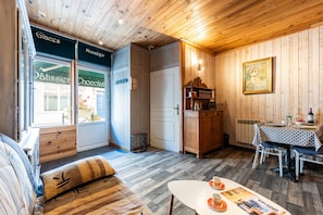 Una habitación acogedora con techo de madera, una mesa de comedor con sillas, un sofá y vista a una chocolatería.