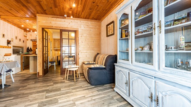A wooden interior with a sofa, dining table, and cabinets.