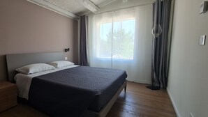 A bedroom with a bed, nightstands, a window with curtains, and a ceiling with exposed beams. - Apartment in semi-detached villa nestled in the Ragusa countryside (Ragusa)