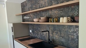 A modern kitchen with a wooden countertop, black sink, and patterned backsplash. - Apartment in semi-detached villa nestled in the Ragusa countryside (Ragusa)