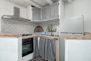 Una cocina con gabinetes blancos, estufa, horno y refrigerador.