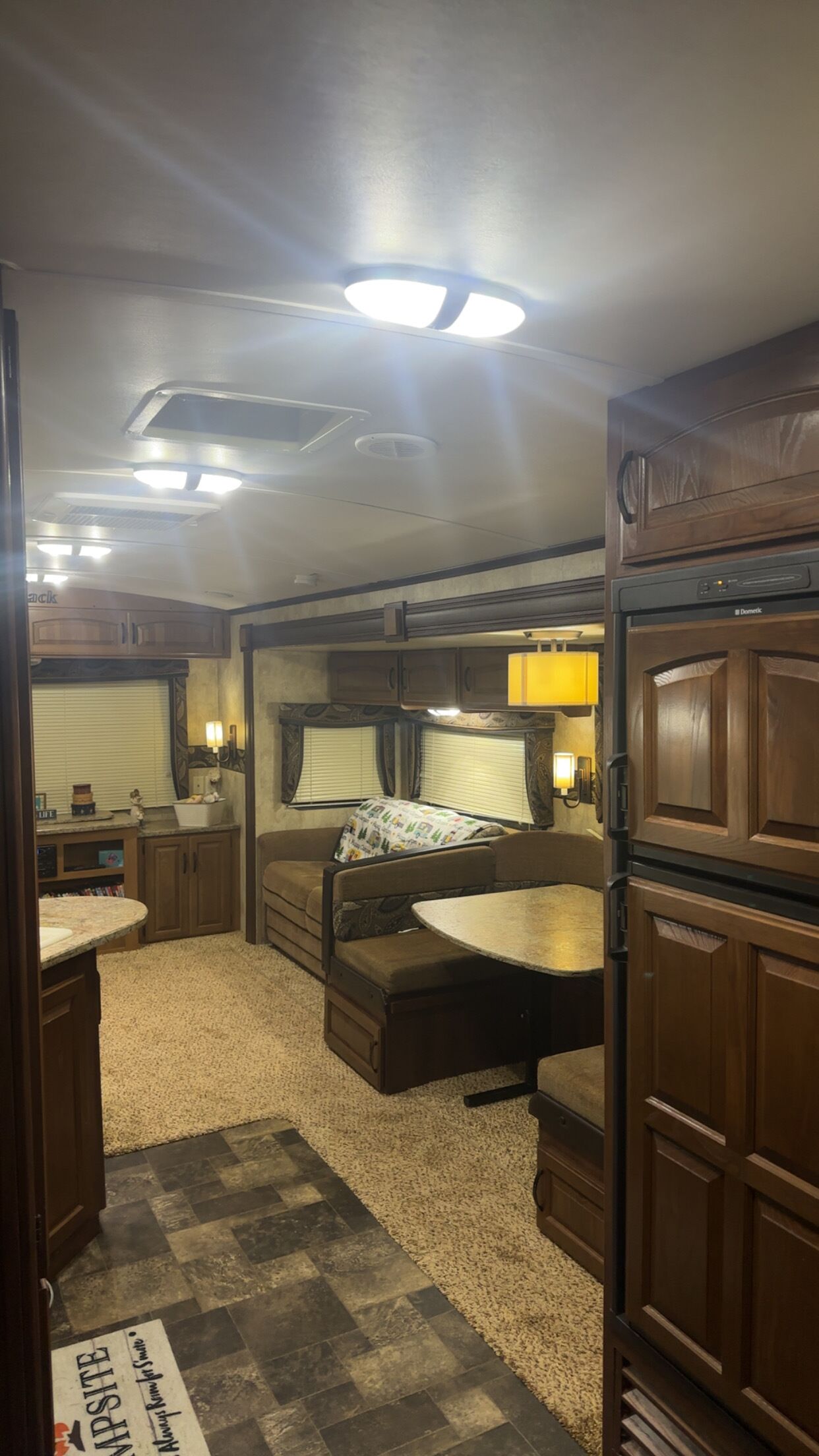 Interior compacte d'un autocaravana amb cuineta, un llit sofà i zona de menjador.