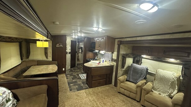 An RV interior with a kitchenette, seating area, and a bathroom. - Cozy RV in charming McClure with AC, WiFi. Happy travels (McClure)