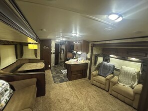 An RV interior with a kitchenette, seating area, and a bathroom. - Cozy RV in charming McClure with AC, WiFi. Happy travels (McClure)