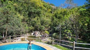 A swimming pool with a wooden deck, surrounded by lush greenery and a natural landscape. - Eco Resort Hotel Villa São Romão (Nova Friburgo)