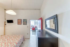 Une chambre à coucher avec un lit, une commode, une télévision et un miroir.