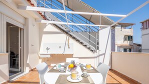 A terrace with a table set for breakfast, a staircase, and a view of the adjacent building. - Holiday Home 'Piazzetta Al Mare' with Sea View, Wi-Fi and Air Conditioning (Palermo)