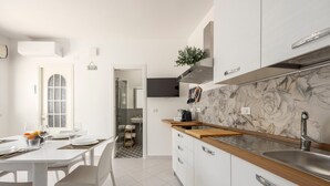 A modern kitchen with white cabinetry, a marble backsplash, and a wooden countertop. - Holiday Home 'Piazzetta Al Mare' with Sea View, Wi-Fi and Air Conditioning (Palermo)
