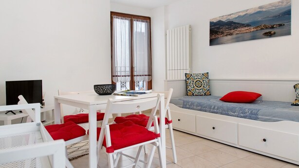 Une pièce moderne comprenant une table à manger, des chaises, un canapé et un tableau représentant un paysage côtier.