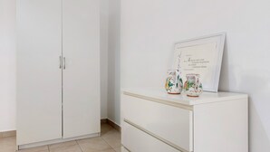 Une armoire blanche à deux portes et une petite commode blanche agrémentée d’objets décoratifs.