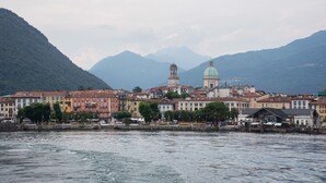 Une vue urbaine sur le front de mer, avec des bâtiments historiques, un dôme imposant et des montagnes en arrière-plan.