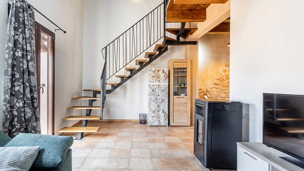A living room with a staircase, a TV, and a cabinet. - Estudio 'Vencejos' con Wi-Fi en Ademuz (Ademuz)