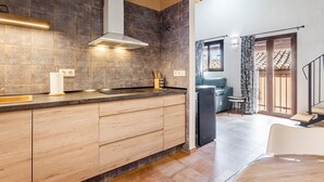 A modern kitchen with a large island, a built-in oven, and a dining area with a view of the terrace. - Estudio 'Vencejos' con Wi-Fi en Ademuz (Ademuz)