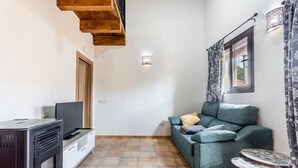 A compact living space with a sofa, a small table, a television, and a fireplace. - Estudio 'Vencejos' con Wi-Fi en Ademuz (Ademuz)