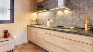 A modern kitchen with a large window, a built-in stove, and a sink. - Estudio 'Vencejos' con Wi-Fi en Ademuz (Ademuz)
