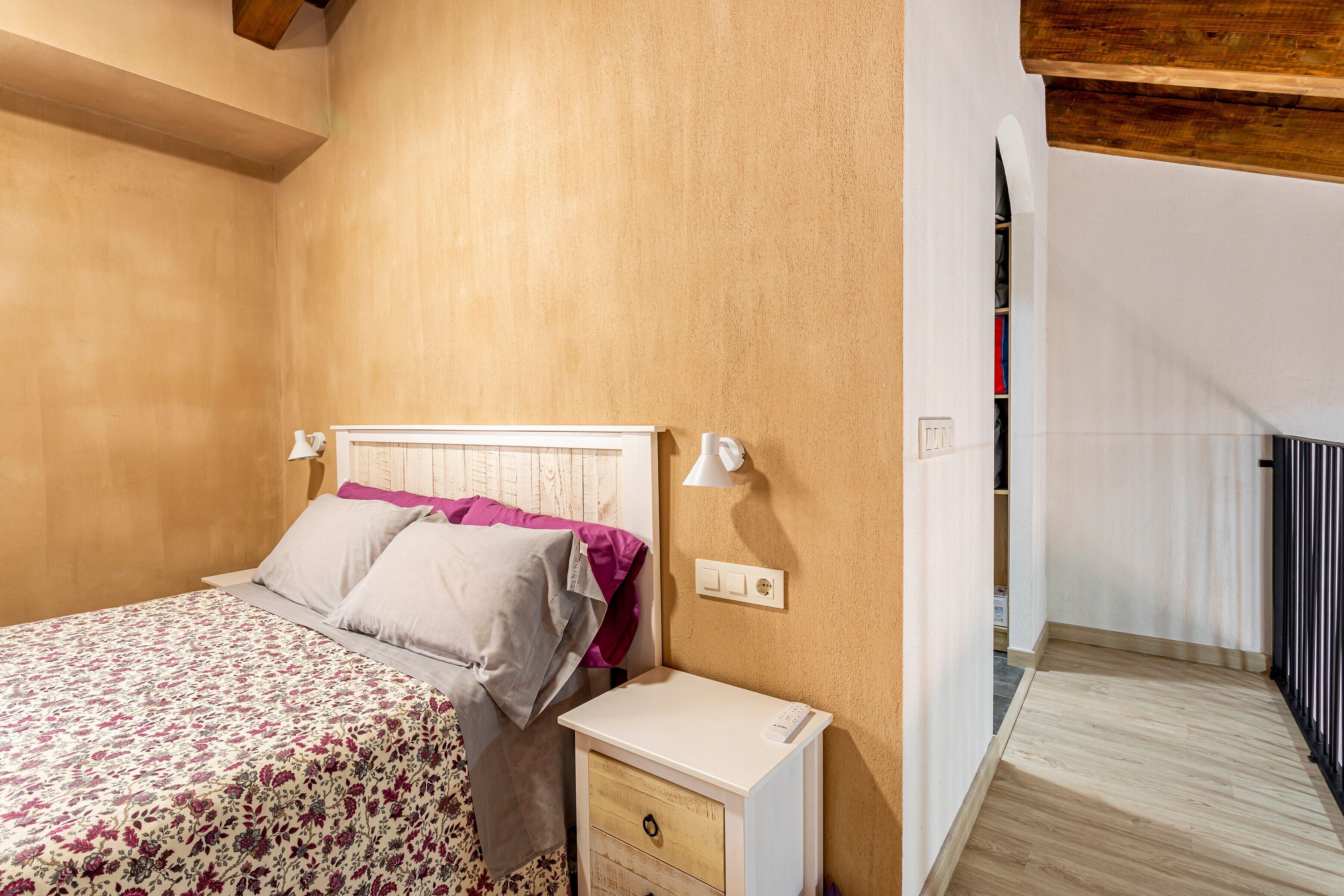 Een slaapkamer met een bed, nachtkastje en een bijzettafeltje.