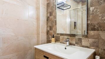 A bathroom with a white sink, a mirror, and patterned tiles.