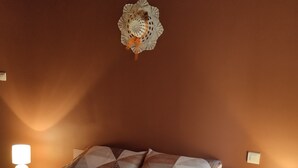 Un dormitorio con una cama, dos lámparas de noche, un reloj de pared y un objeto decorativo sobre la cama.