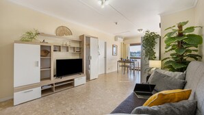 A living room with a TV, sofa, and a dining area with a table and chairs.