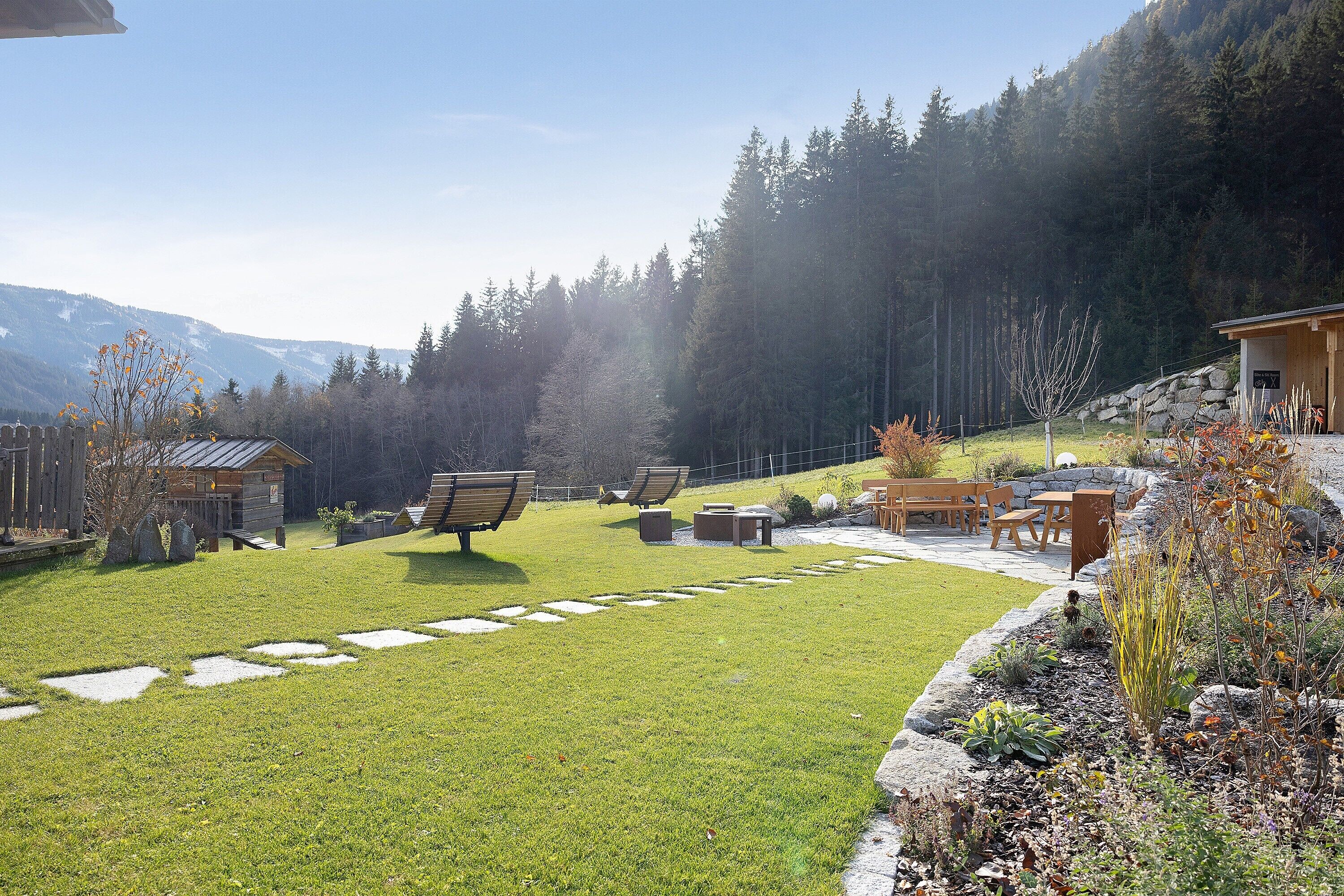 Un jardin bien entretenu, agrémenté d’un chemin de pierres, d’un espace salon extérieur et d’un chalet en bois.
