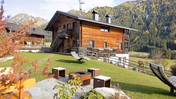 Une cabane en bois dotée d’un balcon, d’un foyer en pierre et d’une terrasse en bois.