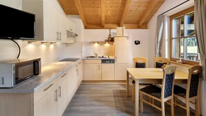 Une cuisine compacte dotée de meubles en bois, d’un four à micro-ondes, d’un évier et d’un coin repas avec des chaises.